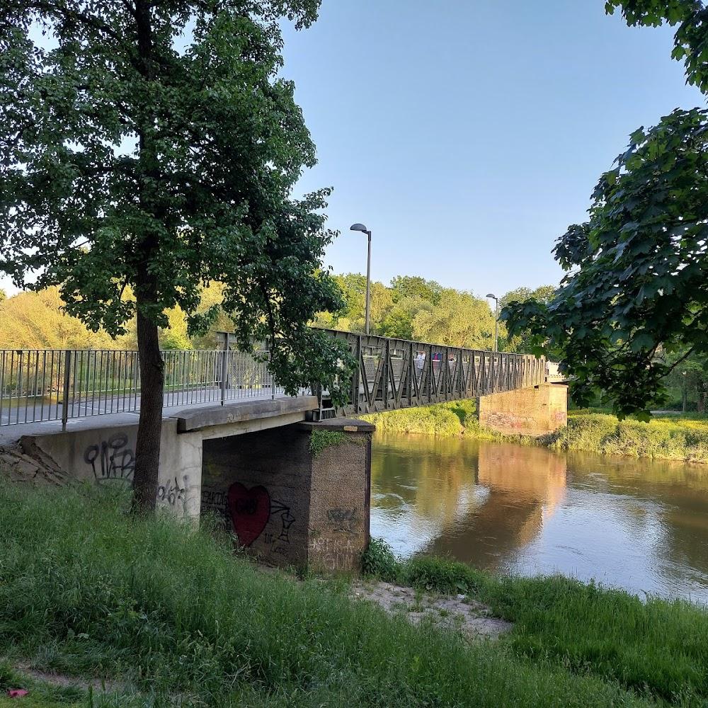 A metal bridge over a river with graffiti on the pillars.